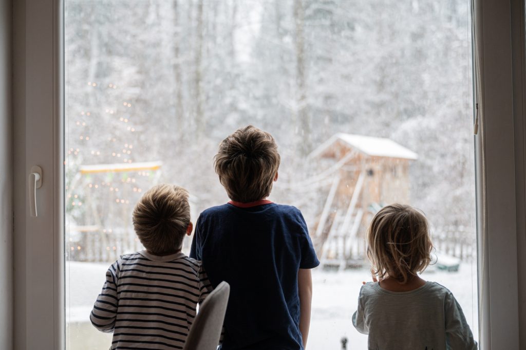 Kids looking out the window while snowing