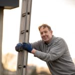 Man leaning on a ladder at sunset
