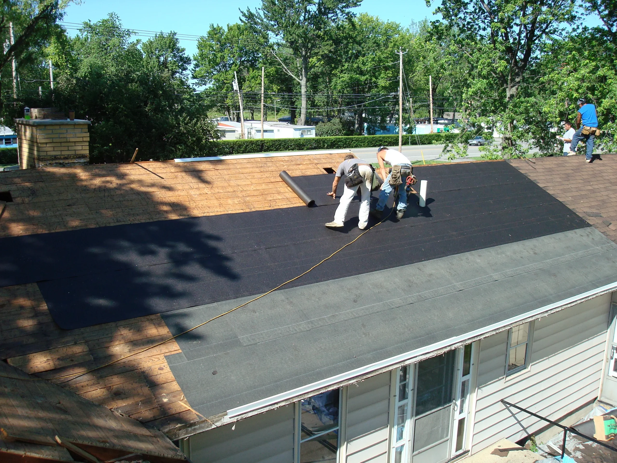 Roof inspection for ice & water shield in Buffalo & Niagara - Professional examining edge of roofing, shield visible under shingles