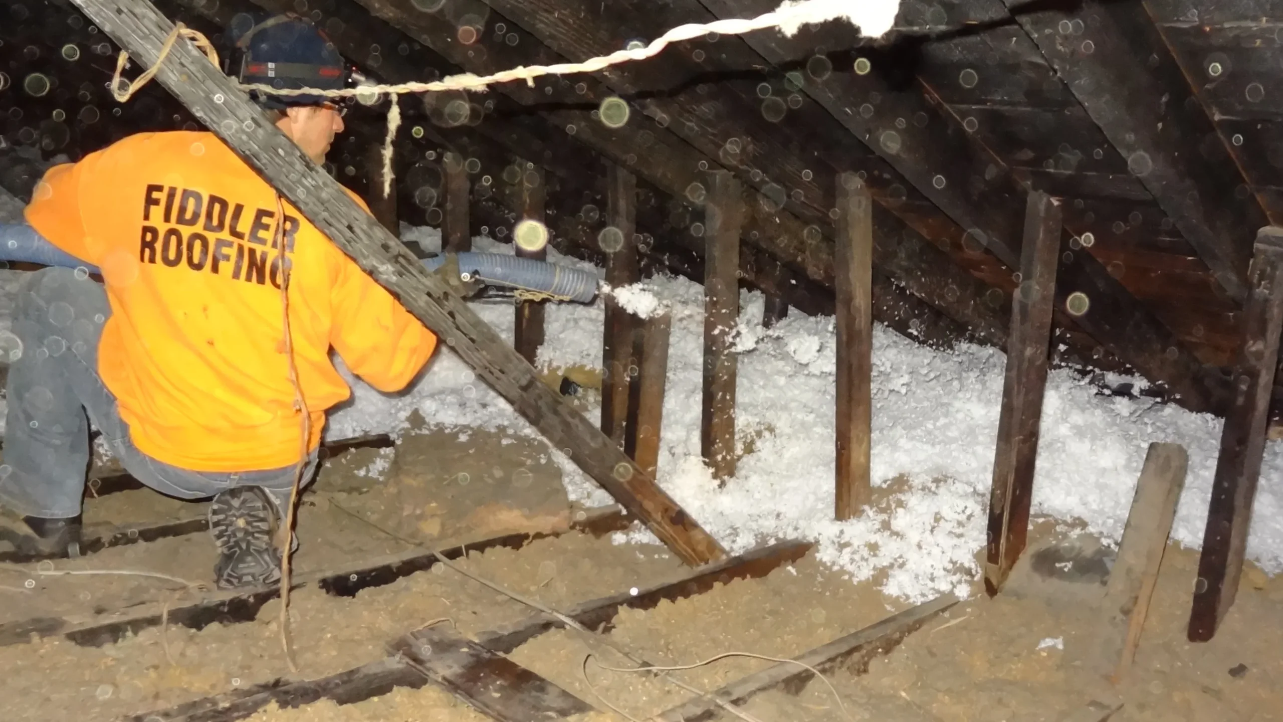 Proper attic insulation in Buffalo & Niagara - Technician inspects warm, well-insulated attic to prevent roof damage