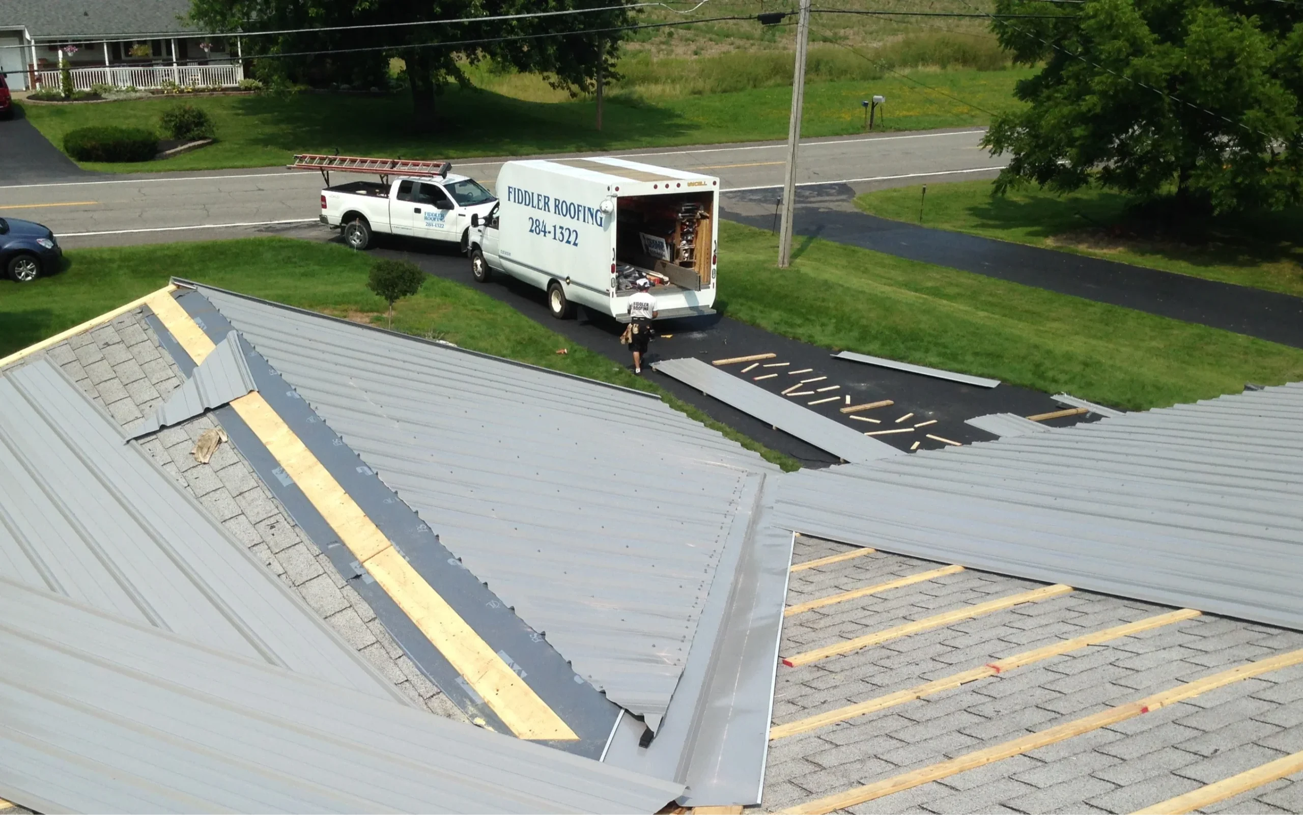 Calm and confident homeowner beside newly installed metal roof, showcasing the truth behind the noisy metal roof myth.