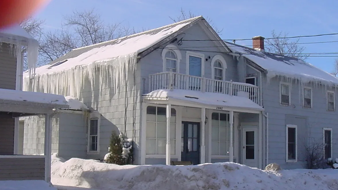 Winter neighborhood with houses showing varying icicle presence and attic insulation levels.